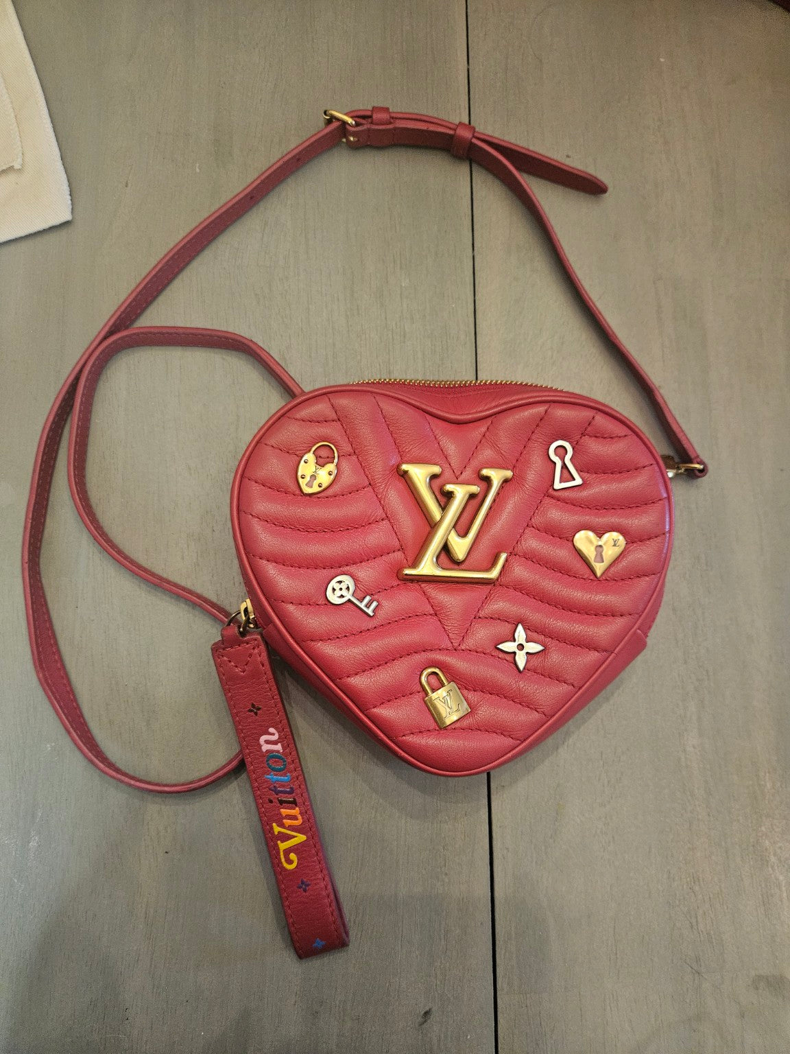 Red Louis Vuitton heart-shaped crossbody with strap and colorful Vuitton tag