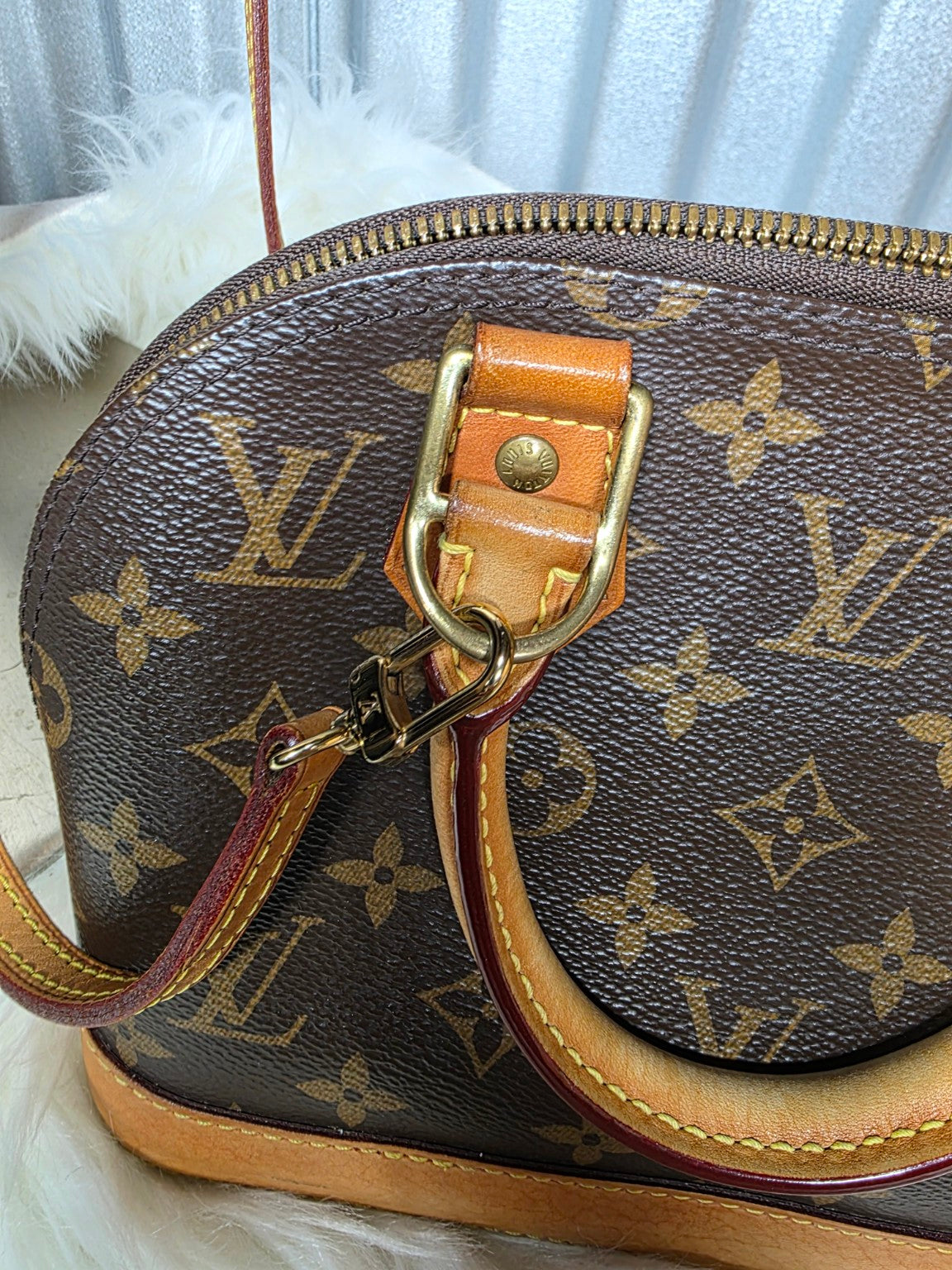 Close-up of monogram canvas, leather handle attachment and hardware